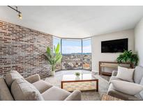 Bright living room featuring brick accent wall, large windows, and comfortable seating area with views of the city skyline at 1625 Larimer St # 2501, Denver, CO 80202