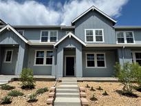 Inviting exterior of gray townhouse with stylish entryway and landscaped front yard with stone details and concrete steps at 17137 W 91St Ln, Arvada, CO 80007