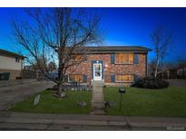 Charming brick home exterior with manicured lawn and mature trees at dusk at 11782 Gilpin St, Northglenn, CO 80233