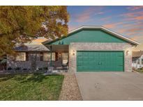 Brick ranch home with green accents, attached garage, and landscaped yard at 1040 S Fulton Ave, Fort Lupton, CO 80621