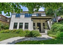 Charming two-story home with a white brick exterior and landscaped front yard with black window frames at 1265 S Gaylord St, Denver, CO 80210