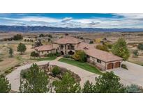 Aerial view of a home with landscaped grounds, circular driveway, and mountain views in the background at 8871 Aspen Leaf Ct, Littleton, CO 80125