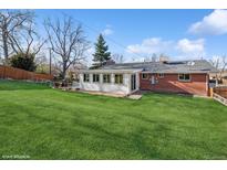 Expansive backyard featuring a well-manicured lawn, patio area, and sunroom addition to the home at 11600 W 31St Pl, Lakewood, CO 80215