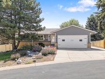 Charming home exterior with a well-manicured front yard, blue siding, a two-car garage, and mature trees at 2155 S Deframe St, Lakewood, CO 80228