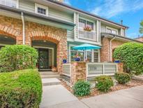 Charming townhome featuring a brick archway, a patio, and manicured landscaping for enhanced curb appeal at 2716 W Greens Dr, Littleton, CO 80123