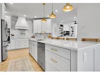 Bright, white kitchen featuring a large island with quartz countertops and gold hardware at 12408 W 83Rd Ave, Arvada, CO 80005
