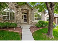 Charming home featuring a stone facade, arched entry, and well-maintained landscaping at 6900 W Grant Ranch Blvd # 88, Denver, CO 80123