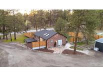 Charming single-story brick home with fenced yard and stone patio surrounded by mature trees at 34480 County Road 17, Elizabeth, CO 80107