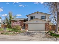 Charming two-story home features a brick facade, attached two car garage, and a well-maintained front yard at 7140 S Reed Ct, Littleton, CO 80128