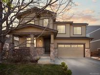 Inviting two-story home with stone accents, covered porch, and a spacious two-car garage with a beautiful sunset at 41 Garner Ln, Erie, CO 80516