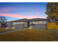 Charming gray brick and siding home with well-manicured lawn at dusk at 8217 W 71St Pl, Arvada, CO 80004