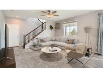 Bright living room features contemporary furnishings, a ceiling fan, and a staircase at 22255 E Mansfield Pl, Aurora, CO 80018