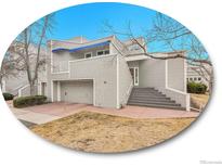 Inviting two-story home featuring a covered balcony, attached garage, and elevated front entry with manicured landscaping at 9200 E Cherry Creek South Dr # 29, Denver, CO 80231