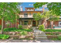 Charming two-story brick home featuring a landscaped front yard, covered porch, and a classic architectural design at 1451 N Gilpin St, Denver, CO 80218