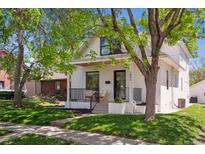Charming two-story home boasts a well-manicured lawn, complemented by trees and a welcoming front porch at 2844 Quitman St, Denver, CO 80212