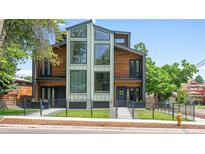 Modern home with wooden exterior, black trim, and large windows creating a sleek and inviting facade at 2702 Lowell Blvd, Denver, CO 80211