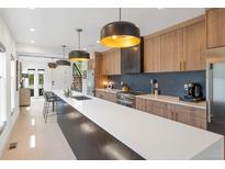 Modern kitchen boasts a long center island, sleek countertops, stylish pendant lights, and stainless steel appliances at 2702 Lowell Blvd, Denver, CO 80211