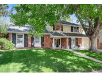 Charming two-story home with a brick facade, a well-manicured lawn, and mature trees in a suburban setting at 6624 S Sycamore St, Littleton, CO 80120