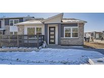 Contemporary home exterior with stone accents and a modern front door with a snow-covered yard at 6874 Zuni Ct, Denver, CO 80221