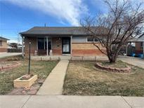 Charming brick home featuring a cozy front porch and well-defined landscaping in a peaceful neighborhood at 7140 Avrum Dr, Denver, CO 80221