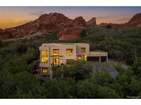 Stunning home nestled in a lush, green landscape, with beautiful red rock formations serving as a scenic backdrop at sunset at 5668 Red Fern Ct, Littleton, CO 80125