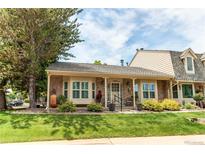 Charming home with brick facade, manicured lawn, and mature tree, offering inviting curb appeal at 7682 S Cove Cir, Centennial, CO 80122