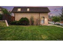 Charming brick two-story home with a well-maintained lawn and lush green bushes and trees at 5573 S Lowell Blvd, Littleton, CO 80123