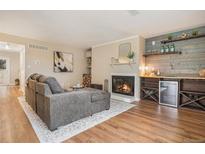 Inviting living room with cozy fireplace, wood floors, and stylish wood shelving and mini fridge at 5573 S Lowell Blvd, Littleton, CO 80123