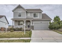 Charming two-story home boasts a well-manicured lawn, gray siding, covered porch, and an attached two-car garage at 8695 Torrey St, Arvada, CO 80007