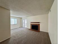 Inviting living room featuring a cozy fireplace and sliding door access to the outdoor space at 12470 E Cornell Ave # 203, Aurora, CO 80014