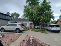Charming single-story home featuring a well-manicured front yard, a large tree, and a vibrant red front door at 3011 S Dexter Way, Denver, CO 80222