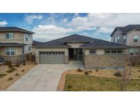 Charming single-story home with a well-manicured lawn and a stone-accented facade at 19409 W 88Th Dr, Arvada, CO 80007