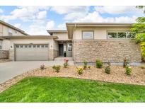 Inviting single-Gathering home featuring a stone facade, manicured lawn, and an attached two-car garage at 19409 W 88Th Dr, Arvada, CO 80007