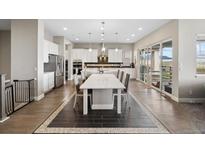 Bright, open kitchen features white cabinets, stainless steel appliances and a spacious island with seating at 19409 W 88Th Dr, Arvada, CO 80007