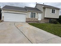 Tan two-story home featuring an attached garage and stone accents, perfect for suburban living at 1415 S Pitkin Ct, Aurora, CO 80017