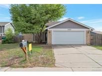 Charming home featuring a two-car garage, brick accents, a mature tree, and a well-maintained front lawn at 18950 E Kent Cir, Aurora, CO 80013