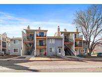 Two-story townhome featuring a private balcony, grey siding, and well-maintained front yard landscaping at 6011 Yarrow St # C, Arvada, CO 80004