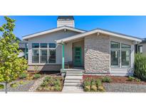 Charming home exterior with stone accents, landscaped garden, and a bright green front door at 10179 E 59Th North Pl, Denver, CO 80238