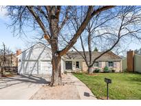 Charming brick home with a well-manicured lawn, mature trees, and a welcoming front entrance at 6997 S Poplar Way, Centennial, CO 80112