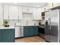 Modern kitchen featuring stainless steel appliances, subway tile backsplash, and two-tone cabinetry with gold hardware at 1227 Yost St, Aurora, CO 80011