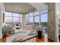 Bright and airy living room featuring concrete accents, expansive windows, and wood floors with city views at 1700 Bassett St # 1612, Denver, CO 80202