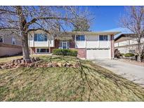 Charming brick and siding home featuring an attached two car garage and mature landscaping at 12861 W Jewell Cir, Lakewood, CO 80228