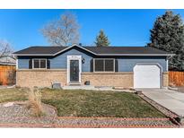 Charming single-story home featuring a brick facade, blue siding, and a well-maintained front yard at 9731 W Polk Dr, Littleton, CO 80123