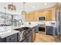 Modern kitchen features an island with a farmhouse sink, stainless steel appliances, and quartz countertops at 9139 Flora St, Arvada, CO 80005