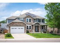 Charming two-story home featuring stone accents, a well-manicured lawn, and solar panels at 9467 W Plymouth Ave, Littleton, CO 80128