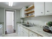 Bright kitchen featuring granite countertops, white cabinets, and floating wood shelves at 9995 E Harvard Ave # 155, Denver, CO 80231