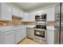 Bright kitchen features white cabinets, stainless steel appliances, and stylish backsplash at 635 S Alton Way # 6A, Denver, CO 80247