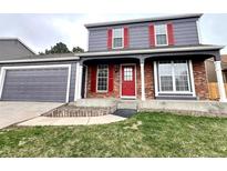Charming two-story home featuring a brick facade, red door and shutters, and an attached garage at 19828 E Brown Pl, Aurora, CO 80013