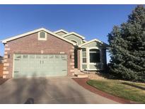 Charming brick home featuring an attached two-car garage, well-kept lawn, and shade tree at 1998 E 100Th Pl, Thornton, CO 80229