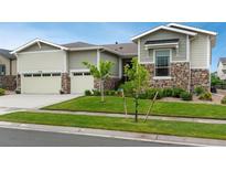 Charming two-story home featuring a manicured lawn, stone accents, and an attached two-car garage at 23130 E Del Norte Cir, Aurora, CO 80016